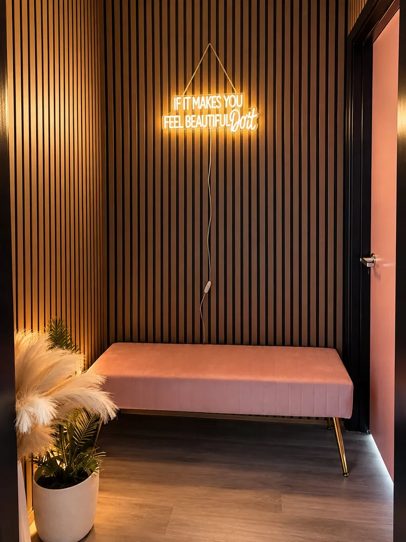 Waiting nook with a pink bench, plants and a neon sign